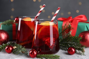 Gözlüklü lezzetli Sangria içkisi ve gri desenli masa üzerindeki Noel süslemeleri, yakın plan.