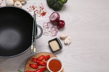 Wok, yemek çubukları ve beyaz ahşap masa üzerindeki farklı ürünler. Metin için boşluk