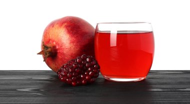 Nar suyunu bardakta, tohumları ve meyveleri beyaz arka planda siyah ahşap masada tazeleyen