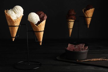 Dondurma külahları siyah ahşap masada koyu arkaplanda.