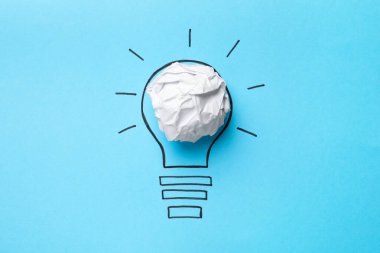 Fikir konsepti. Kırışık kağıttan yapılmış ampul ve açık mavi arkaplan üzerine çizim, üst görünüm