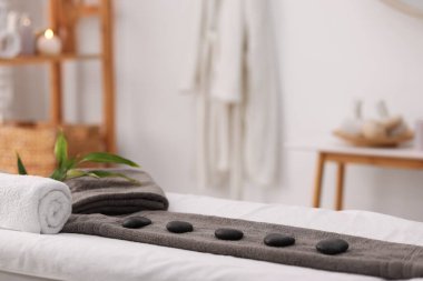 Eğlence merkezindeki masaj masasının üzerinde düzenlenmiş spa taşları olan havlu.