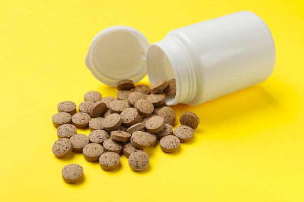 Vitamin pills and bottle on yellow background