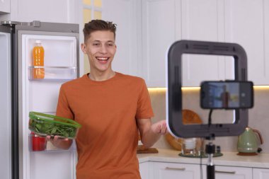 Gülümseyen yemek blogcusu mutfakta video kaydederken bir şey anlatıyor