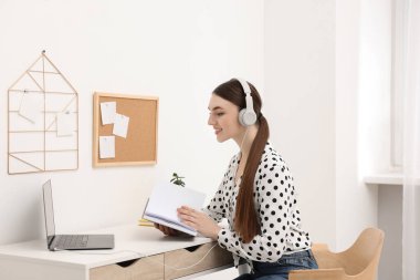 E-öğrenme. İçerideki masada online ders sırasında dizüstü bilgisayar kullanan genç bir kadın.