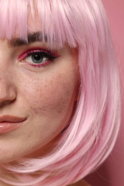 Parlak makyajlı güzel bir kadın ve pembe arka planda sahte çiller, yakın plan.
