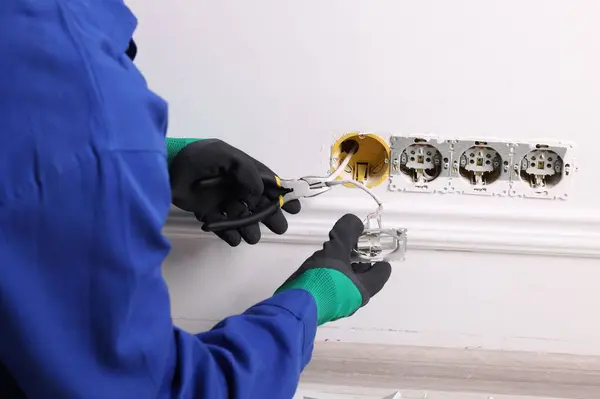 Professional repairman fixing power sockets with pliers indoors, closeup