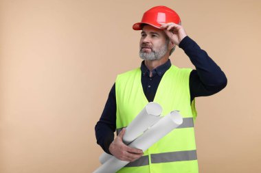 Kasklı mimar bej arka planda taslak tutuyor. Metin için boşluk