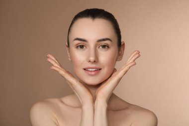 Portrait of beautiful young woman on light brown background