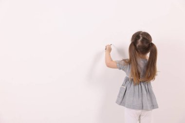 Beyaz duvarlara resim çizen küçük bir kız. Metin için boşluk