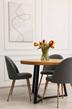 Yemek odasındaki masanın üstünde güzel laleler olan vazo.