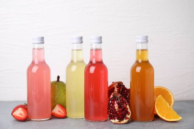 Cam şişelerde lezzetli kombu çayı ve gri masada beyaz arka planda taze meyveler.