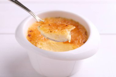 Beyaz masadaki kaseden kaşıkla leziz bir creme brulee alıp yakın plan çekiyoruz.