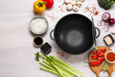 Wok, yemek çubukları ve beyaz ahşap masa üzerinde farklı ürünler, düz yatak. Metin için boşluk