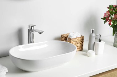 İçinde güzel Alstroemeria çiçekleri ve banyo lavabosunun yanında tuvalet malzemeleri olan vazo.