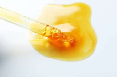 Açık gri arkaplanda pipetten damlayan nemlendirici serum, yakın plan