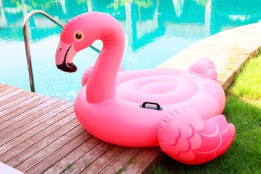 Lüks bir tatil köyünde yüzme havuzunun yanındaki tahta güvertede flamingo şeklinde süzül.