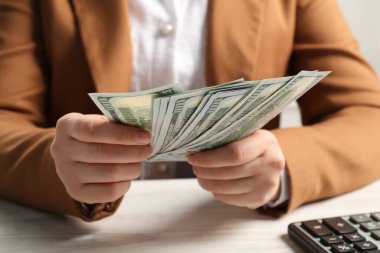 Para değişimi. Beyaz ahşap masada elinde dolar banknotları tutan kadın.