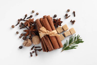 Beyaz masada farklı baharatlar, fındıklar ve köknar dalları var.