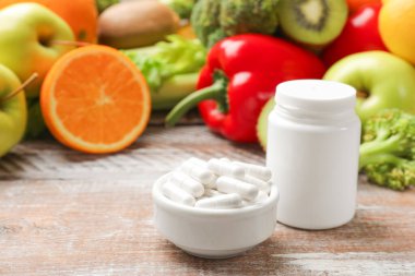 Beslenme takviyeleri. Plastik şişe, hap ve gıda ürünleri ahşap masada, metin için yer