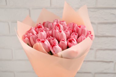 Beyaz tuğla duvarın yanında güzel pembe laleler, yakın plan.