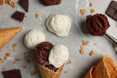 Lezzetli dondurma kepçeleri, çikolata parçaları ve açık mermer masa üzerinde waffle konileri ile düz kompozisyon