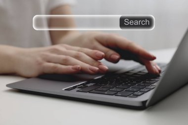 İnternet sitesinin arama çubuğu dizüstü bilgisayarda. Masada bilgisayar kullanan kadın, yakın plan.