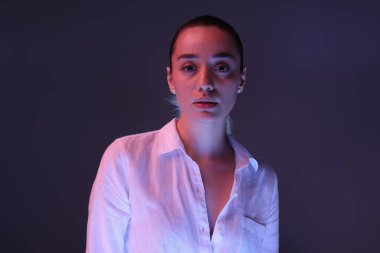 Koyu mor arka planda, neon ışıkları olan güzel bir genç kadının portresi.