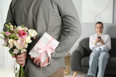 Bir erkek çiçek buketi saklar ve sevgili karısı için kapalı bir yerde hediye verir.