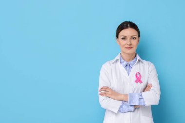 Açık mavi arka planda pembe kurdeleli Mammolog, yazı için yer var. Göğüs kanseri farkındalığı