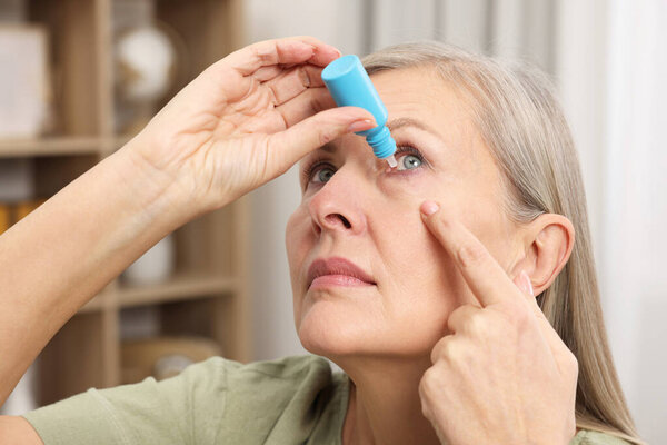 Woman applying medical eye drops at home
