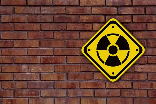Radioactive sign on brick wall, space for text. Hazard symbol