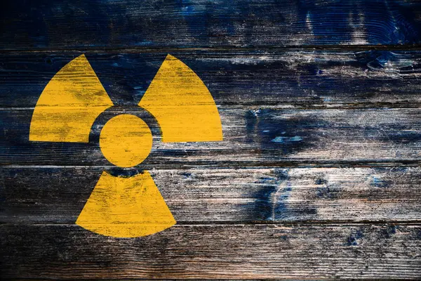 Radioactive sign on wooden background, space for text. Hazard symbol