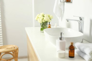 Banyo aksesuarları, lavabo ve güller banyoda.
