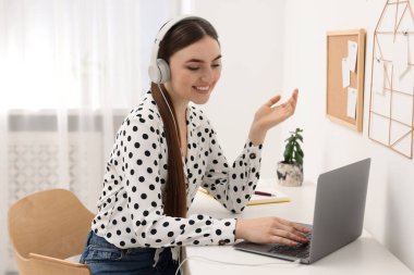 E-öğrenme. İçerideki masada online ders sırasında dizüstü bilgisayar kullanan genç bir kadın.
