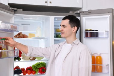 Mutfaktaki buzdolabından sos çıkaran mutlu adam.