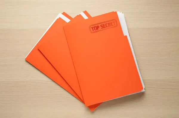 Top Secret stamp. Orange files with documents on wooden table, top view