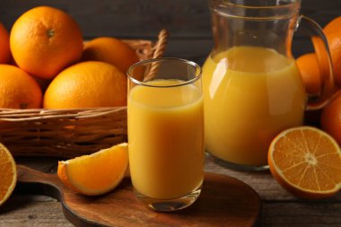 Lezzetli taze portakallar ve meyve suyu ahşap masada, yakın plan.