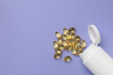 Beyaz şişe ve vitamin kapsülleri menekşe arka planda, üst manzara. Metin için boşluk