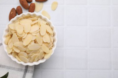 Taze badem taneleri kasede ve fındıklar beyaz fayanslı masada, düz yerde. Metin için boşluk