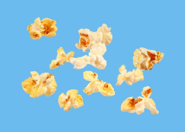 Açık mavi arka planda uçan lezzetli taze patlamış mısır.