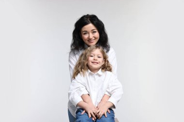 Beyaz arka planda küçük kızı olan güzel bir anne.