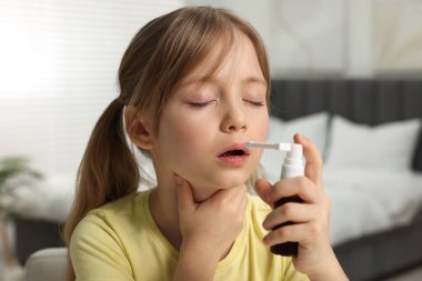 Evde boğaz spreyi kullanan küçük kız.
