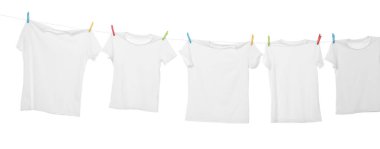 Çamaşır ipinde kuruyan birçok tişört beyaza izole edilmiş.