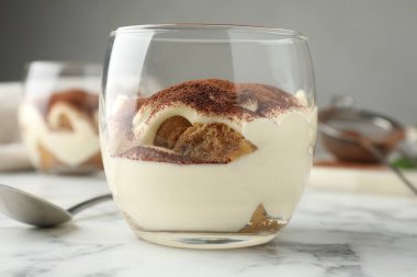 Cam ve kaşıkla nefis tiramisu beyaz mermer masada, yakın plan.