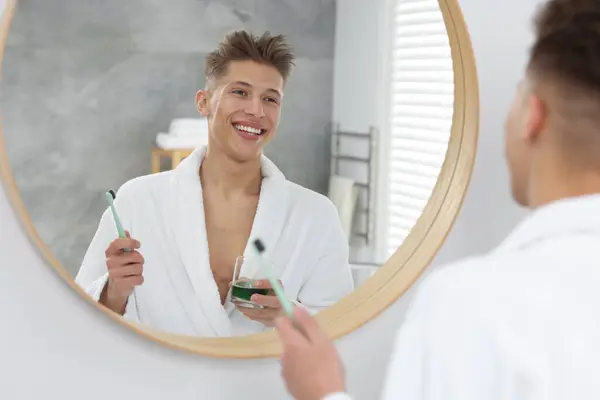 浴室の鏡の近くでマウスウォッシュを使用している若い男 — ストック写真