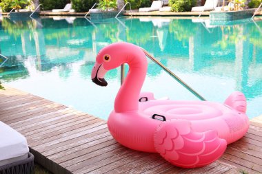 Lüks bir tatil köyünde yüzme havuzunun yanındaki tahta güvertede flamingo şeklinde süzül.