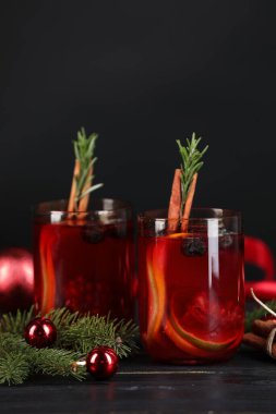 Kadehler, malzemeler ve siyah ahşap masa üzerindeki Noel dekoruyla Aromatik Sangria içeceği.