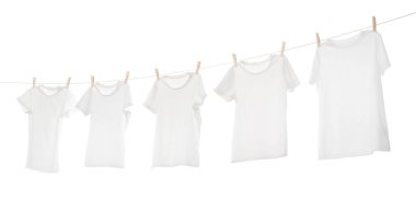 Çamaşır ipinde kuruyan birçok tişört beyaza izole edilmiş.