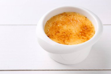 Lezzetli creme brulee kasede beyaz ahşap masada, yakın plan